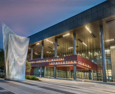Twilight view of Ernest N. Morial Convention Center in New Orleans with illuminated facade and sculpture.